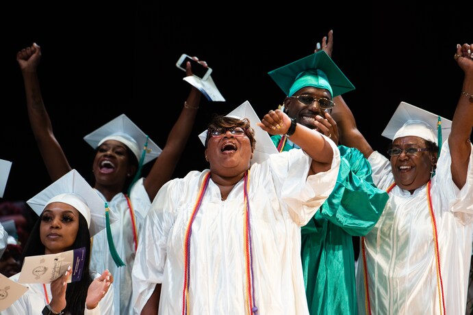 Danielle Corbin, 40, center, and her husband, Stephen Corbin, 33, next to her, cheer during their July 19 graduation from the Goodwill Excel Center, an adult public charter high school in Washington. (Sarah L. Voisin/The Washington Post)